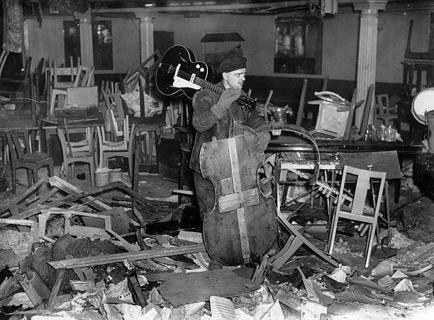 Man saves an intact guitar from amongst the wreckage of the - 1941 Old Photo 1