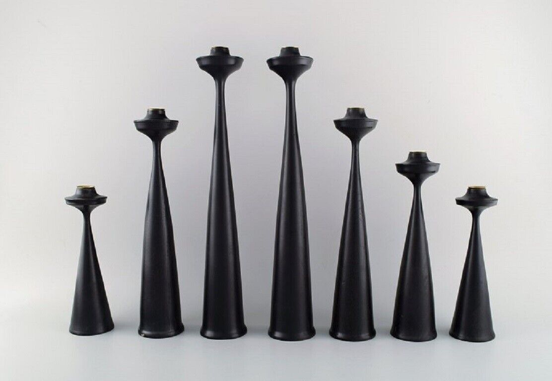 A collection of seven Scandinavian designer candlesticks in wood and brass.