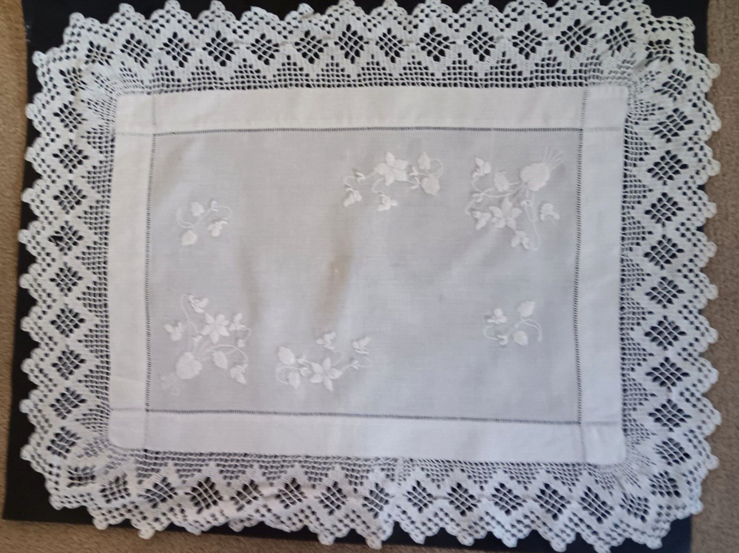 Vintage white rectangular cloth with crochet edges and white embroidery.