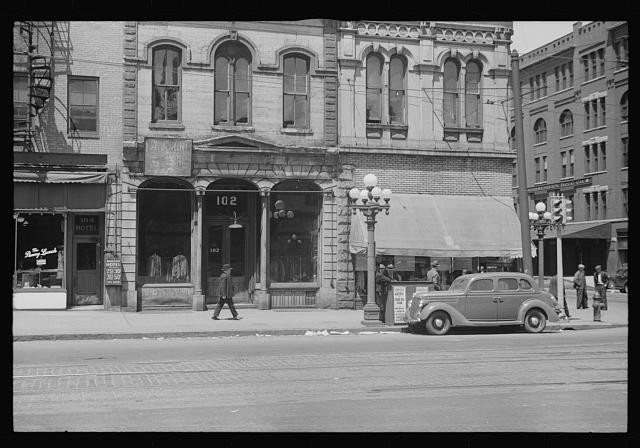 Photo:Downtown Street 1930s Storefronts Hotel Automobiles Pedestrians